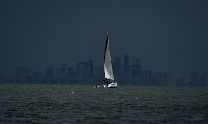 Sailboat under full sail on Biscayne Bay with the Miami downtown skyline behind